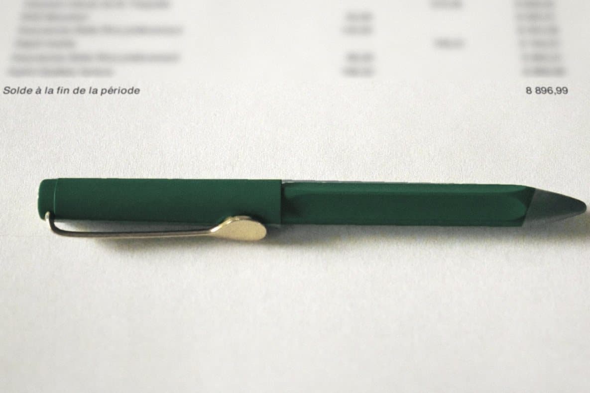 Close-up of the fictional statement's last page: the closing balance, 8,896.99, with a pen resting just below it.